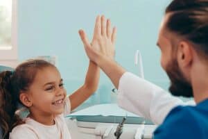 Dentist giving a high five to a happy little girl at a dental clinic,